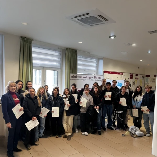 Schülerinnen und Schüler stehen zusammen und halten ihr CAE-Zertifikate in der Hand